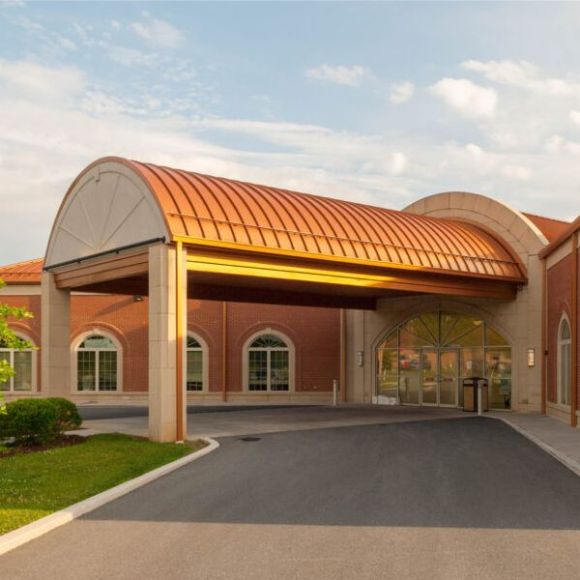 Portico with arched, copper-roofed canopy over entrance to a brick building