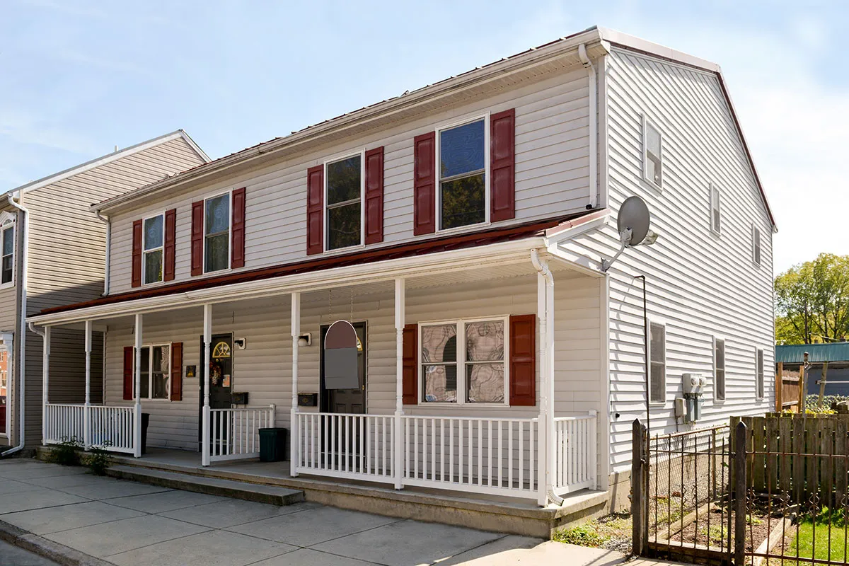 Two-story white house with red shutters and a covered front porch