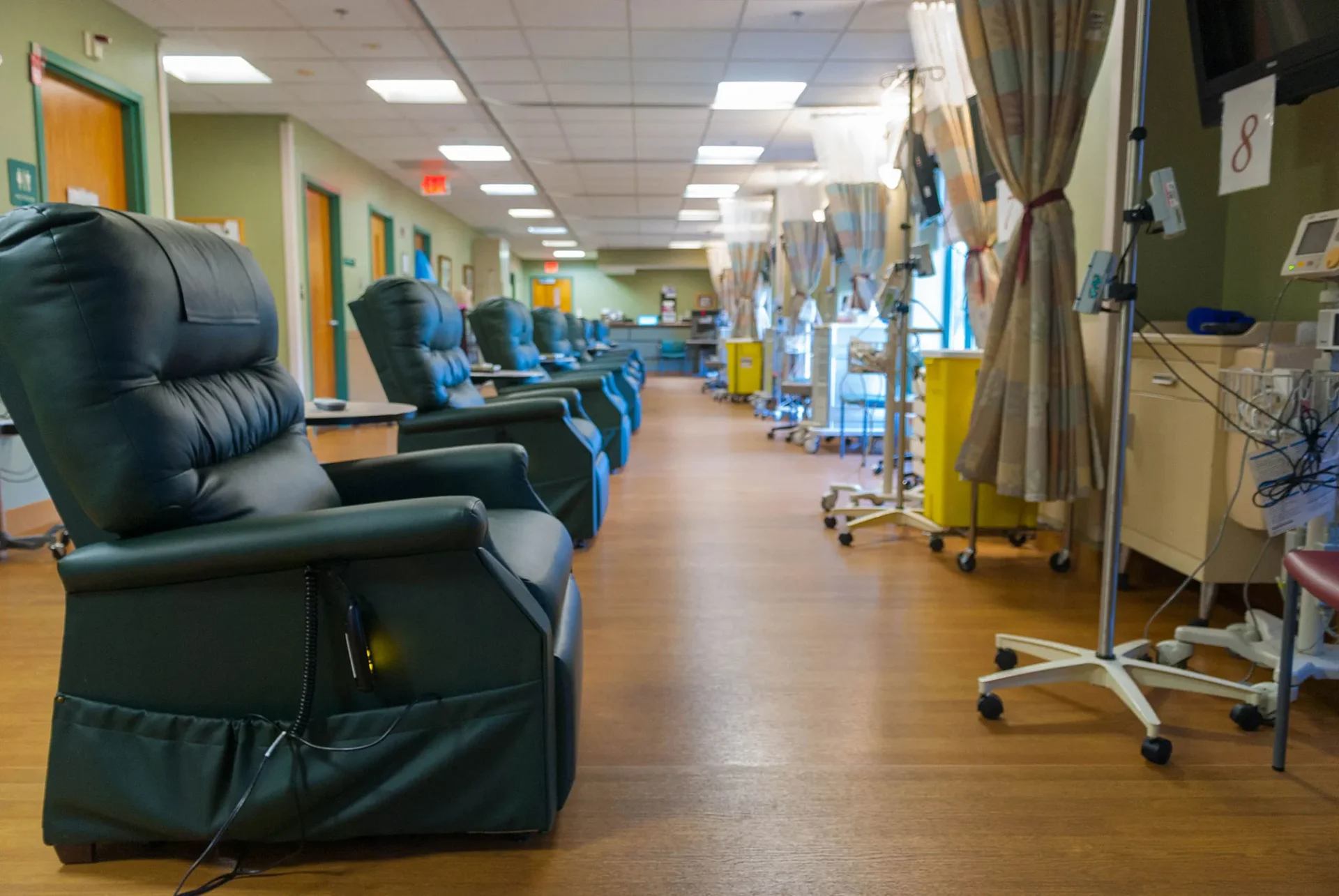 A hospital infusion room with multiple reclining chairs and IV stands