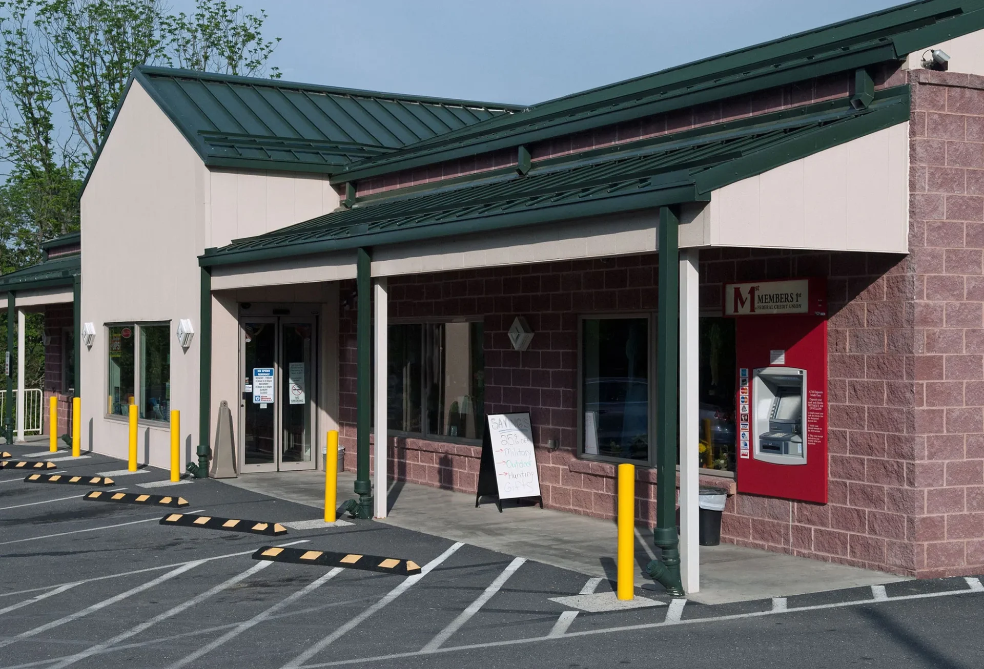 Front view of a bank branch with an ATM and a parking lot