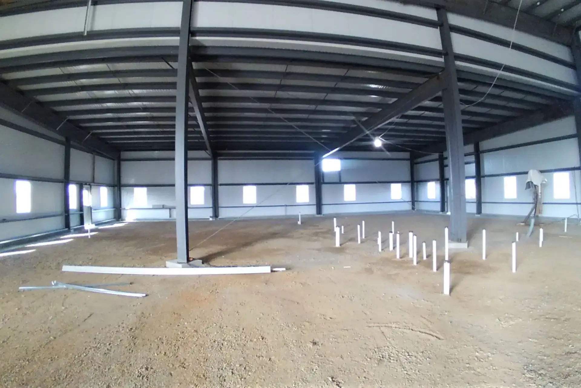 Interior of a large, empty industrial warehouse under construction with visible steel supports