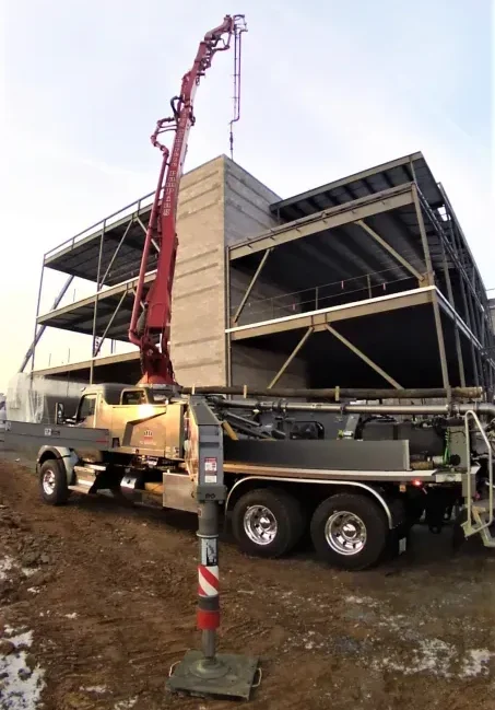 Concrete pump truck with extended boom at a construction site