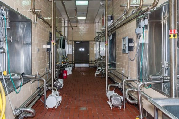 Commercial-Contractor-Hershey-PA-Galbraith1 Industrial kitchen corridor with stainless steel equipment, pipes, and tiled floor, leading to a door at the end